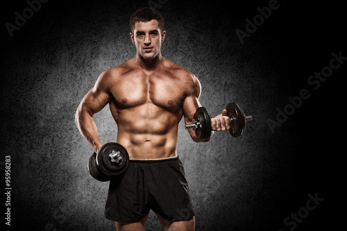 Handsome man with big muscles  posing at the camera in the gym
