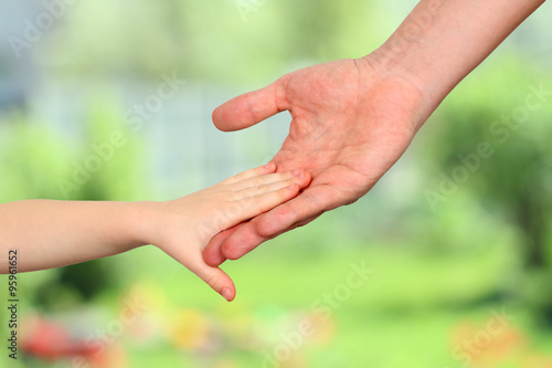 a father  holds the hand of a small child on a green background © Saklakova
