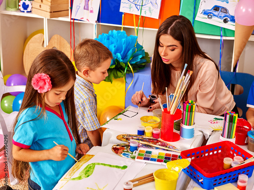 Children with teacher woman painting on paper in  kindergarten