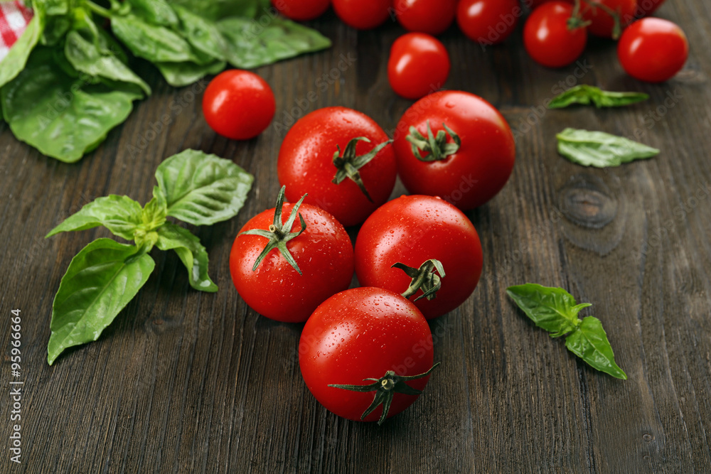 Fresh tomatoes with basil on wooden table close up Fresh tomatoes with basil on wooden table close up
