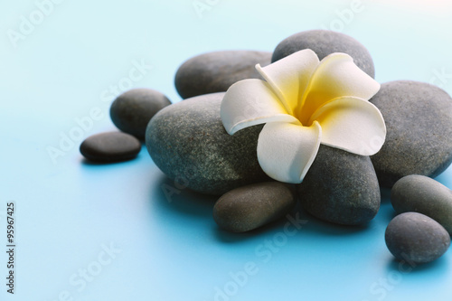 Spa stones with flower on blue background