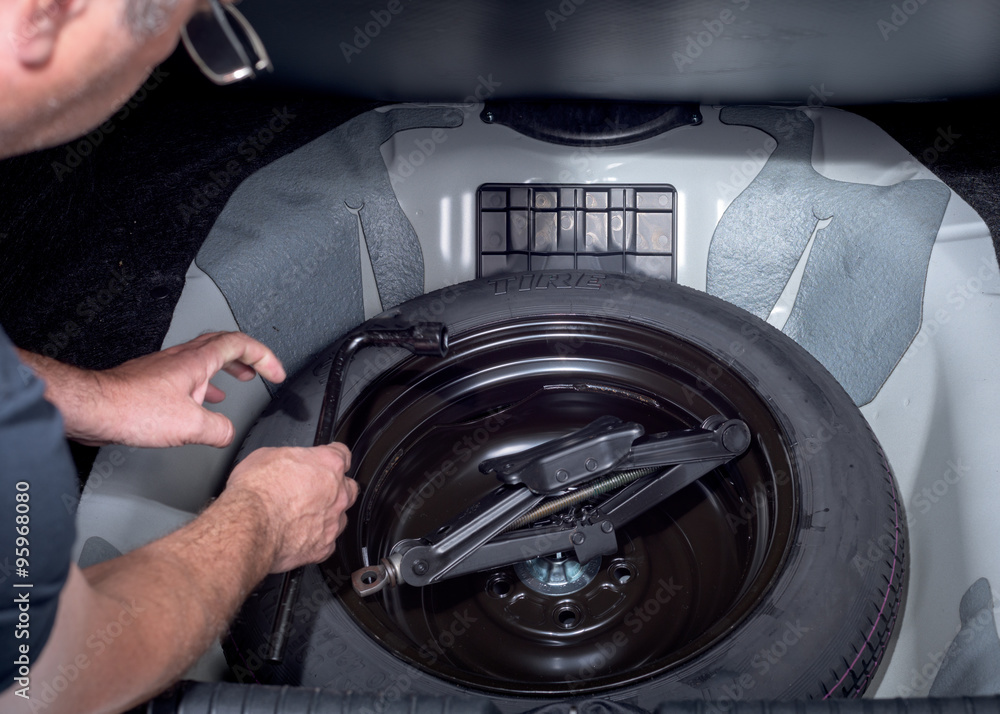 Stockfoto med beskrivningen Spare tire with jack in trunk of a car