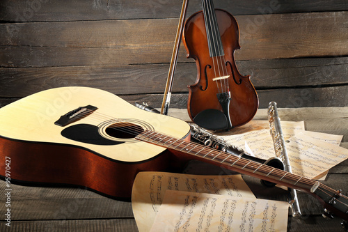 Tablou pe pânză Acoustic guitar, soprano saxophone, violin, flute and note sheets on wooden back