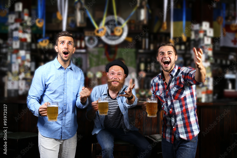 Young men with beer rejoice the victory of their favorite team in the pub Young men with beer rejoice the victory of their favorite team in the pub