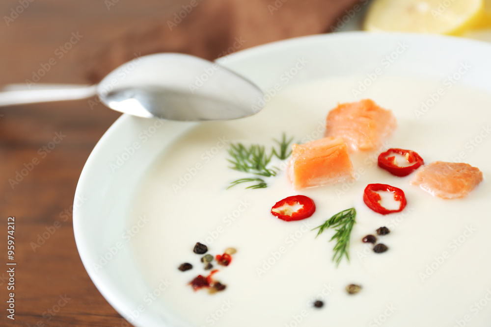 Delicious salmon cream soup with spoon on wooden table, close up Delicious salmon cream soup with spoon on wooden table, close up