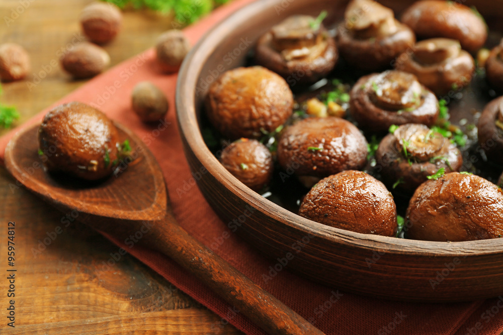 Baked champignons mushrooms with butter, parsley and roasted garlic in brown bowl