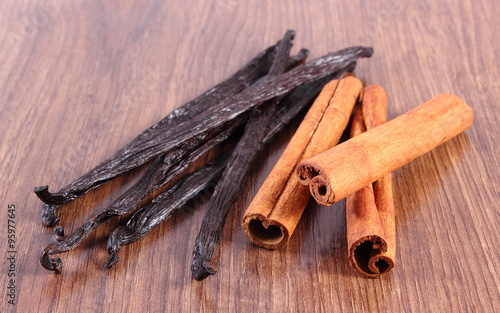 Fototapeta Naklejka Na Ścianę i Meble -  Fragrant vanilla and cinnamon sticks on wooden surface plank