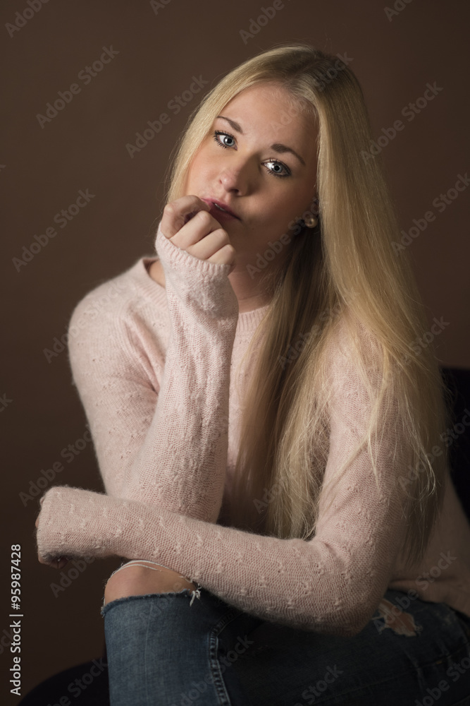 Nachdenkliche blonde Frau im Portrait auf braunem Hintergrund Nachdenkliche blonde Frau im Portrait auf braunem Hintergrund