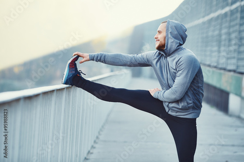 Fototapeta Naklejka Na Ścianę i Meble - Male runner doing stretching exercise