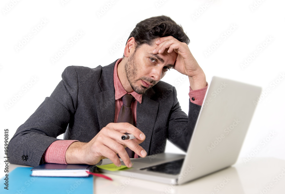 attractive businessman at office desk working on computer laptop looking tired and busy attractive businessman at office desk working on computer laptop looking tired and busy
