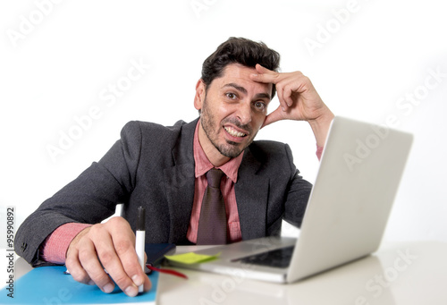 attractive businessman at office desk working on computer laptop looking tired and busy