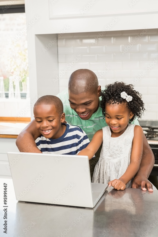 Father using laptop with his children in kitchen Father using laptop with his children in kitchen