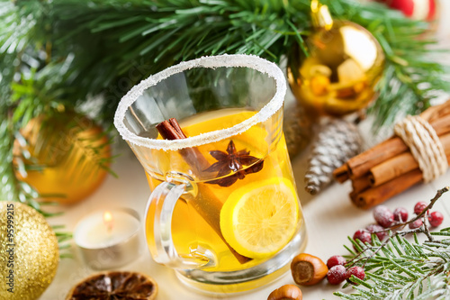 Holiday winter hot citrus drink near Christmas tree with decorations. Lemon tea. #95999215