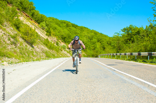 Fototapeta Naklejka Na Ścianę i Meble -  Male cyclist riding a bike on mountain road