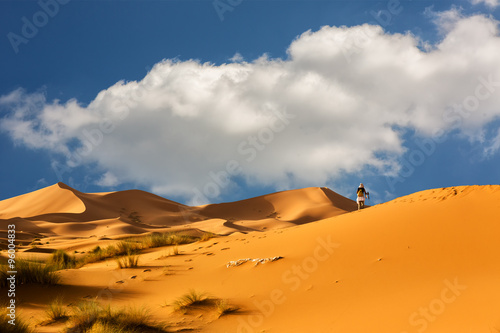 Woman walks through the dunes of Sahara Desert , Morocco