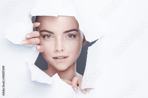 woman looking out from behind a hole in a paper sheet