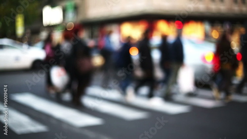 anonymous crowd cross the street into the traffic city in blurred and out of focus context city photo
