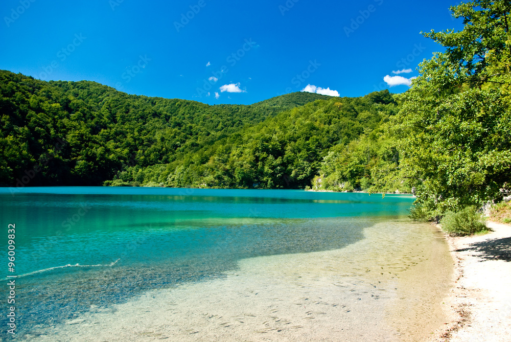 sandy beach, azure water and green trees of Plitvice lakes