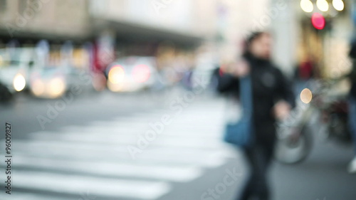 woman cross the street with red traffic light , out of focus urban context in big busy city photo
