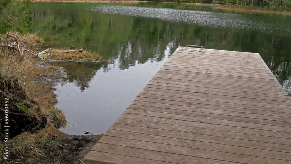 Wooden ledge on the spring water lake. Water is so clear where trees reflection can be seen on the lake Wooden ledge on the spring water lake. Water is so clear where trees reflection can be seen on the lake