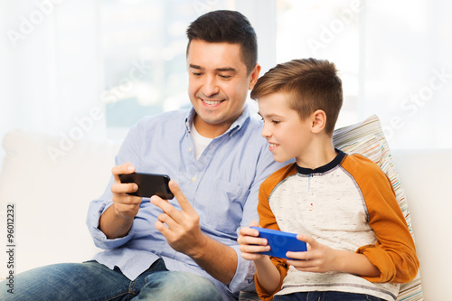 happy father and son with smartphones at home