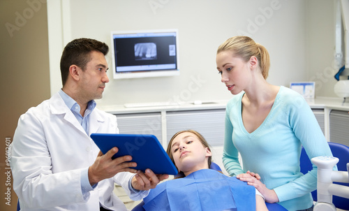 dentist showing tablet pc to girl and her mother