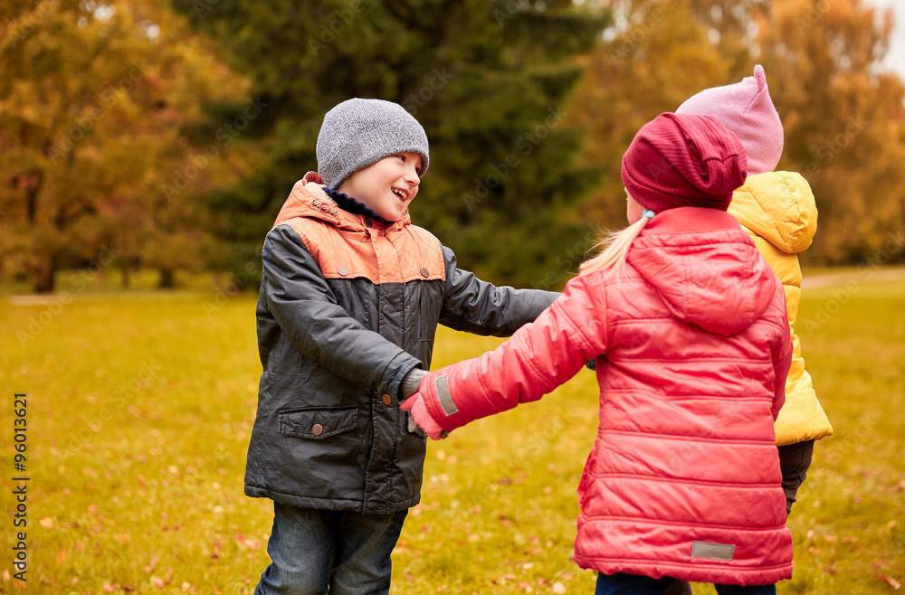 children holding hands and playing in autumn park children holding hands and playing in autumn park