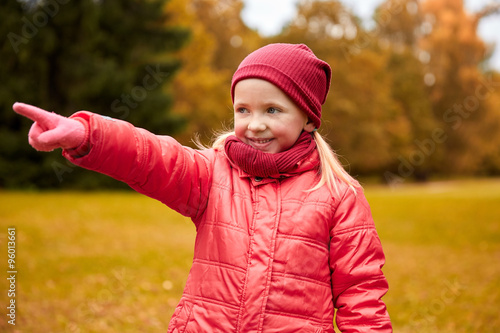 happy little girl pointing finger in autumn park