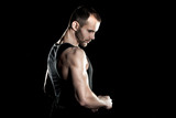 muscular man,  clasps hands in  fist, black background, place for text on the right