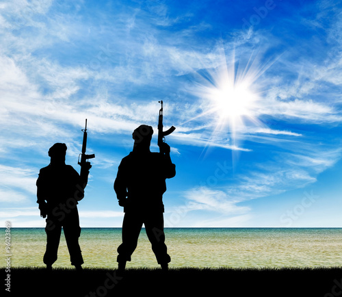 Silhouette of men holding rifles against cloudy sky