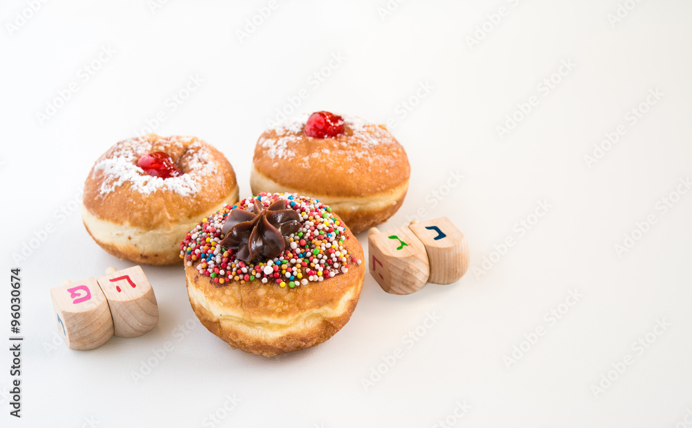 Close up of fresh donuts and wood dreidels  for Hanukkah Jewish Holiday.