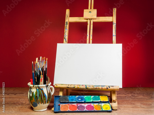 easel palette watercolors and brushes with empty white canvas