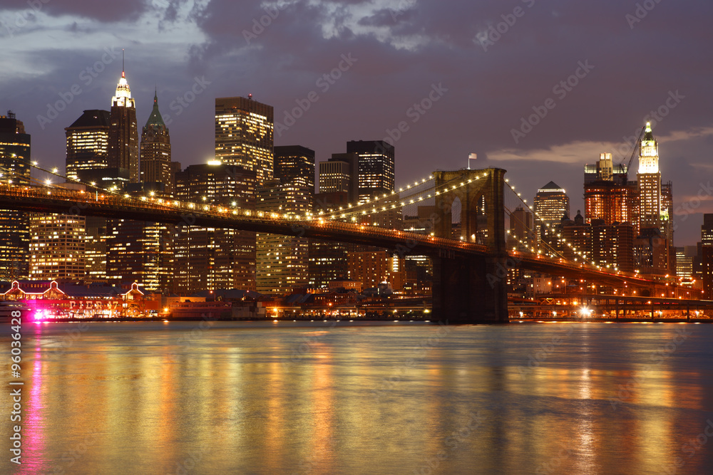The Brooklyn Bridge and Manhattan skyline as seen from across the East River at dusk.