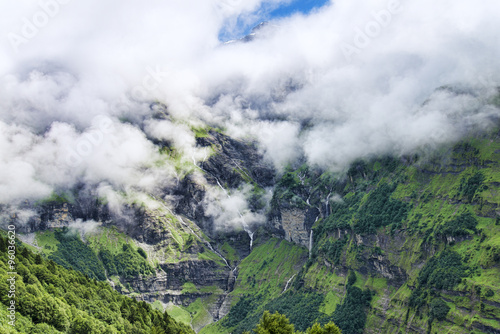 Scenic view of green rocky mountains waterfalls peaks and clouds