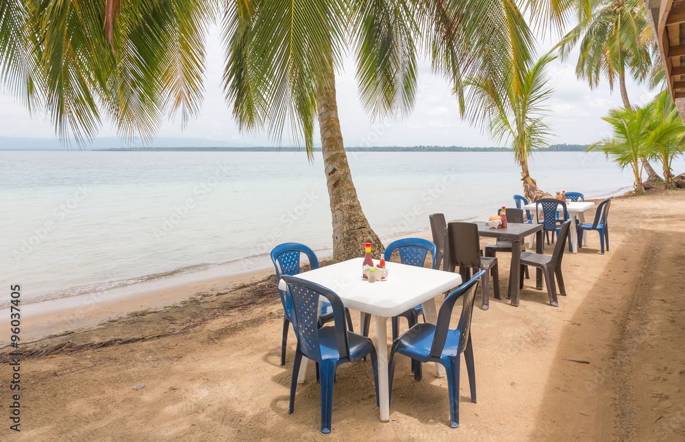 Restaurant tables under the palm trees on the beach