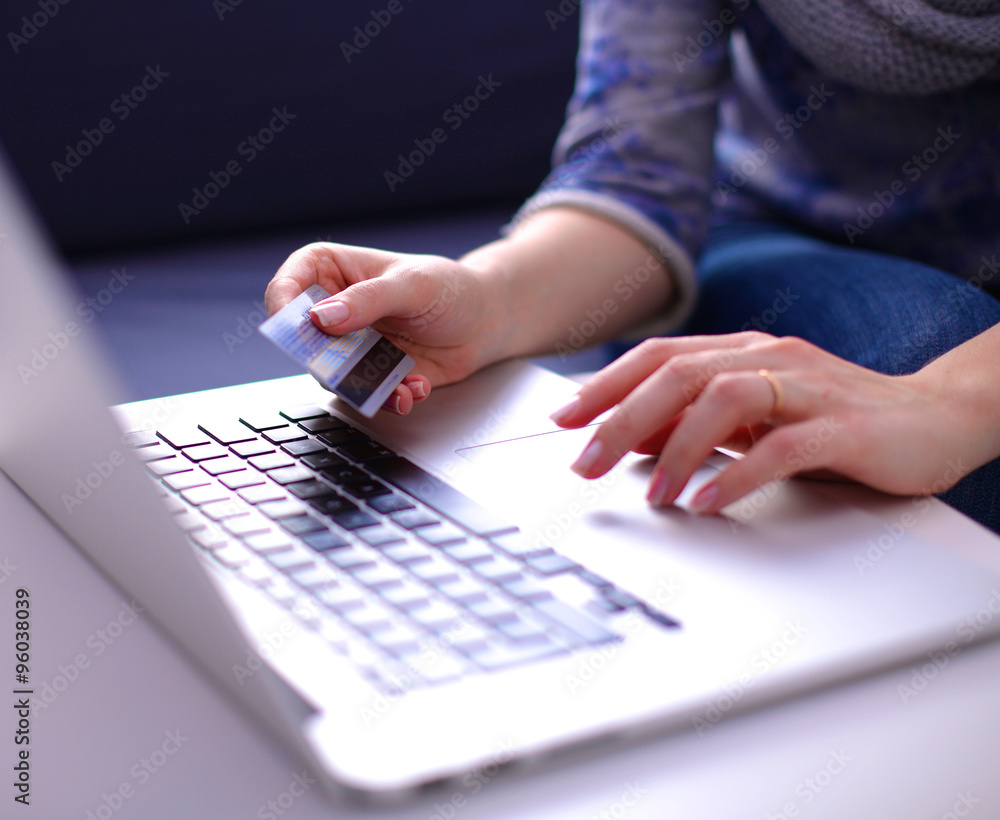 Woman sitting at the desk, shopping with laptop and credit card Woman sitting at the desk, shopping with laptop and credit card