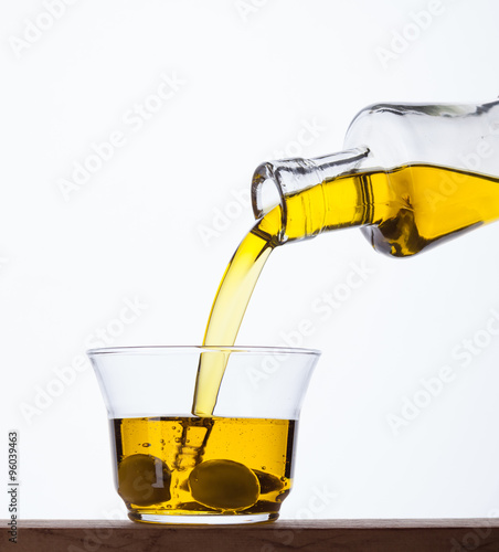 Pouring olive oil from a bottle into a glass