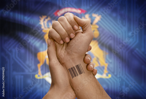 Barcode ID number on wrist of dark skinned person and USA states flags on background - Michigan