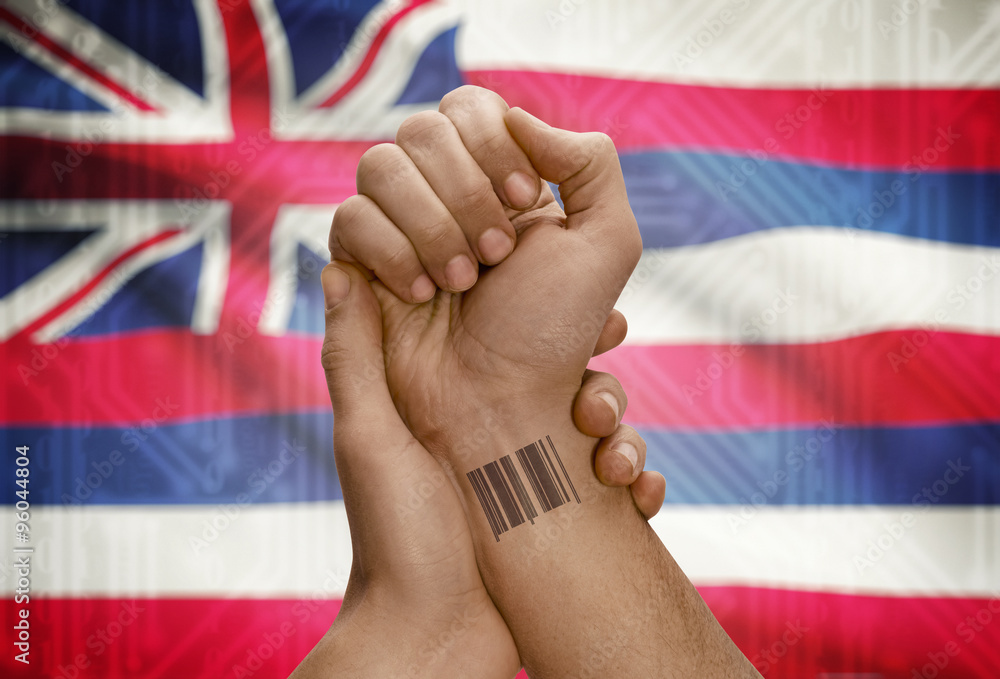 Barcode ID number on wrist of dark skinned person and USA states flags on background - Hawaii
