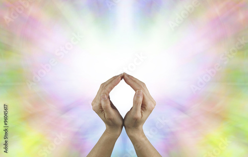 The Circle of Eternal Life - Female hands making an O shape with a vibrant burst of white light energy behind filled by a rainbow colored butterfly shape and plenty of copy space