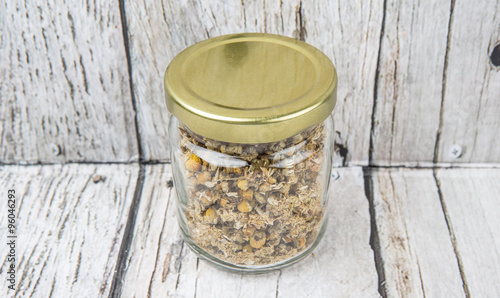 Dried charmomile herbal tea in mason jar over wooden background photo