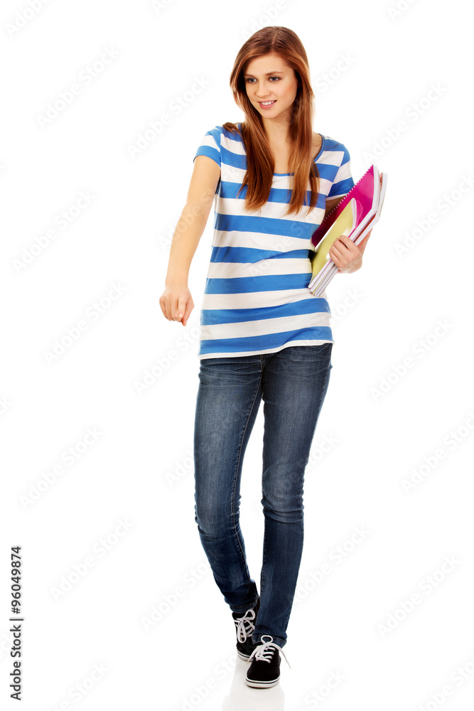 Teenage happy woman holding textbooks and pointing for something Teenage happy woman holding textbooks and pointing for something