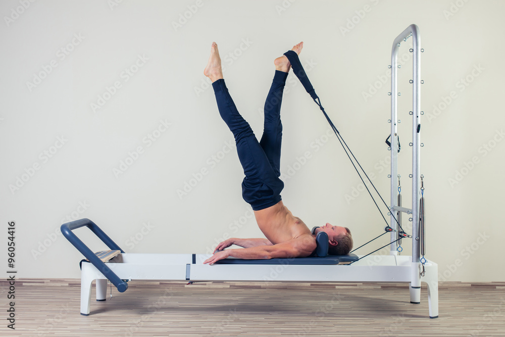 Pilates reformer workout exercises man  at gym indoor