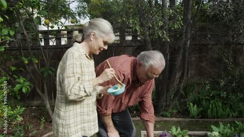 Senior couple standing eating in garden Senior couple standing eating in garden