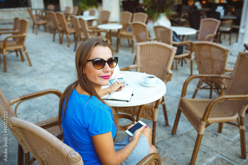 Young pretty modern blogger using smartphone and makes notes in © vladstar