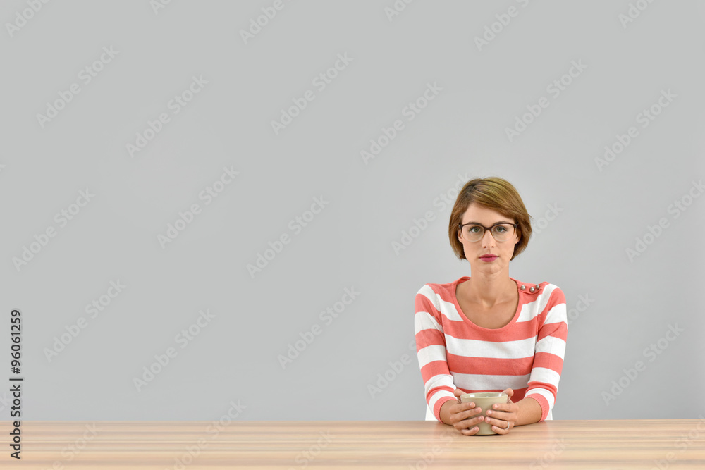 Young woman sitting at table with cup of tea - obrazy, fototapety, plakaty 