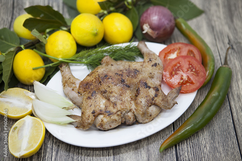 Fried chicken tapaka on porcelain plate with lemon and chilli onion  on the wooden background photo