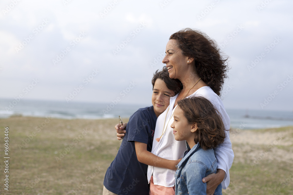 Madre abrazando a sus hijos en la playa