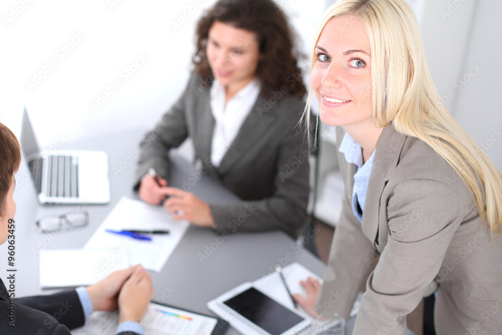 A group of business people at a meeting on the background of office. Focus on a beautiful blonde A group of business people at a meeting on the background of office. Focus on a beautiful blonde