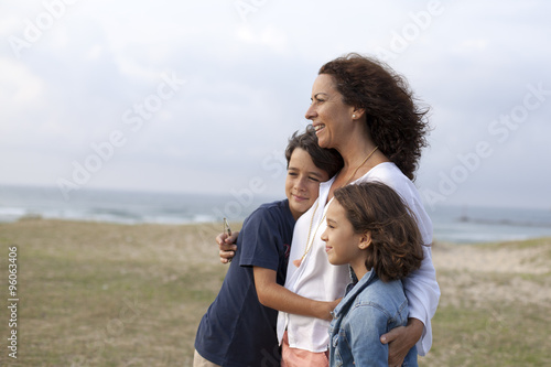 Obraz na płótnie Madre abrazando a sus hijos en la playa w salonie